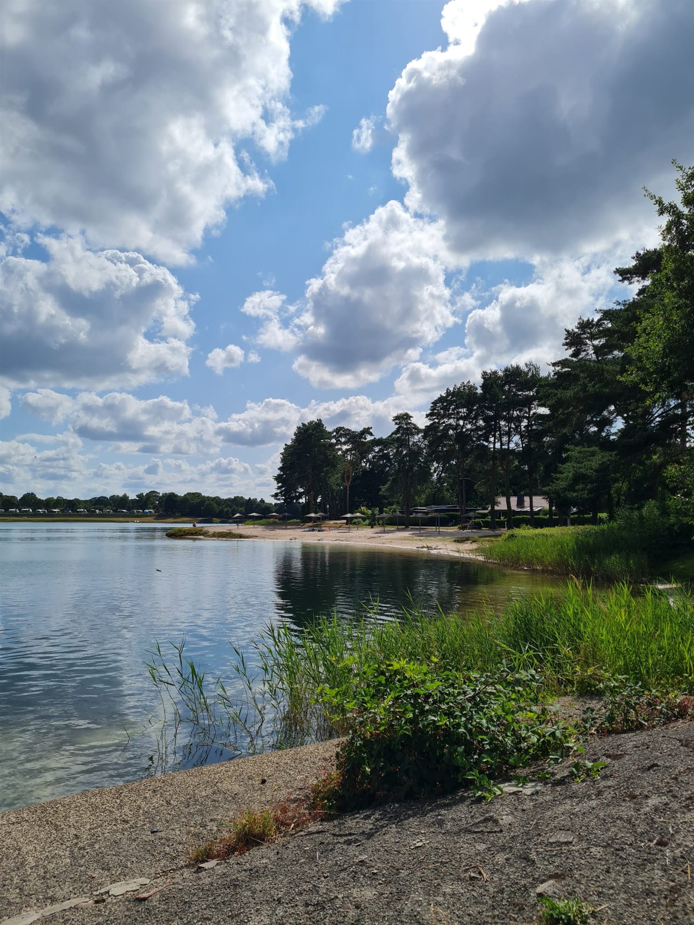 Ruhiger Bernsteinsee unter Sommerwolken