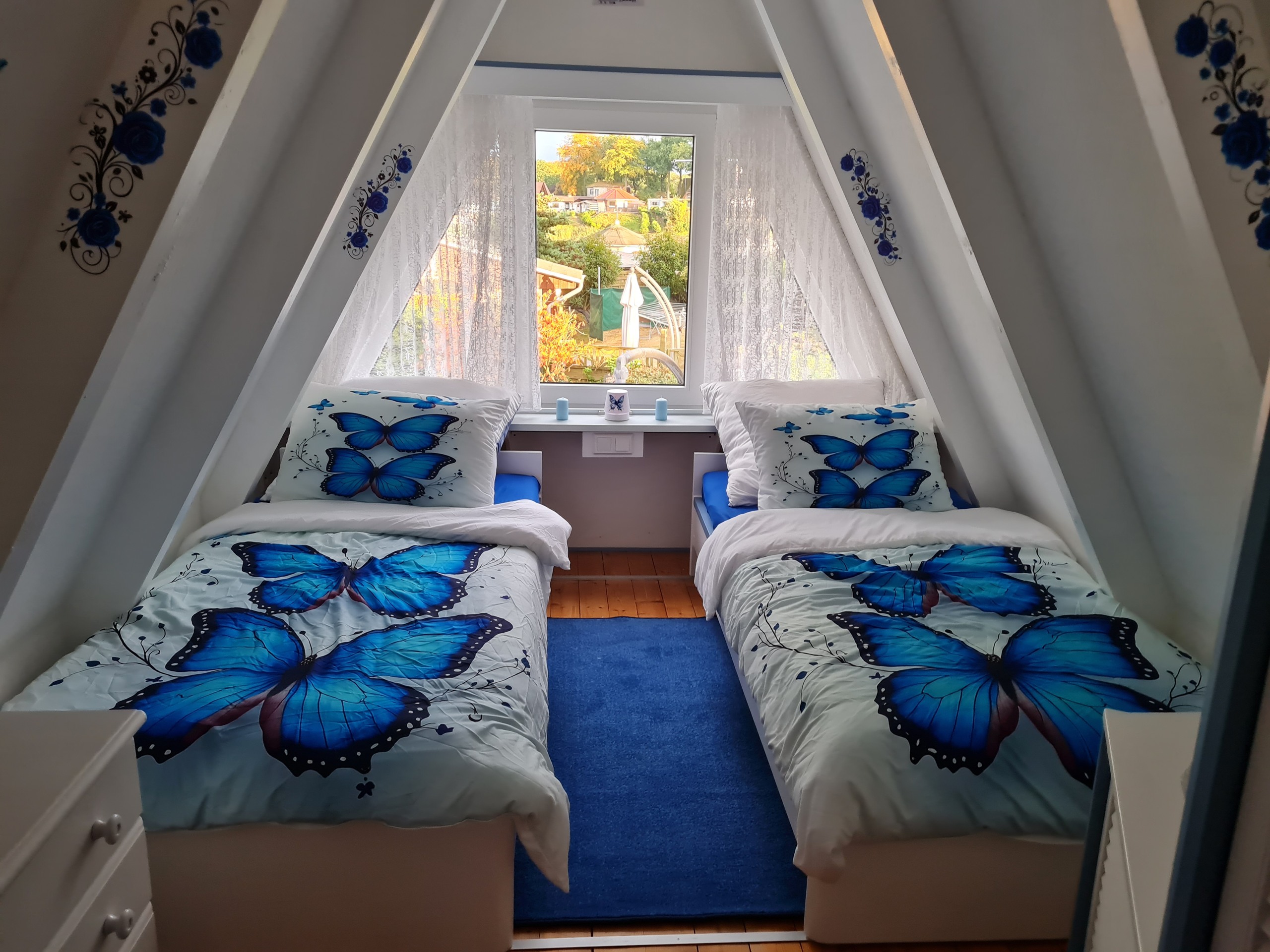 Schlafzimmer mit zwei Einzelbetten und blauen Schmetterlingen