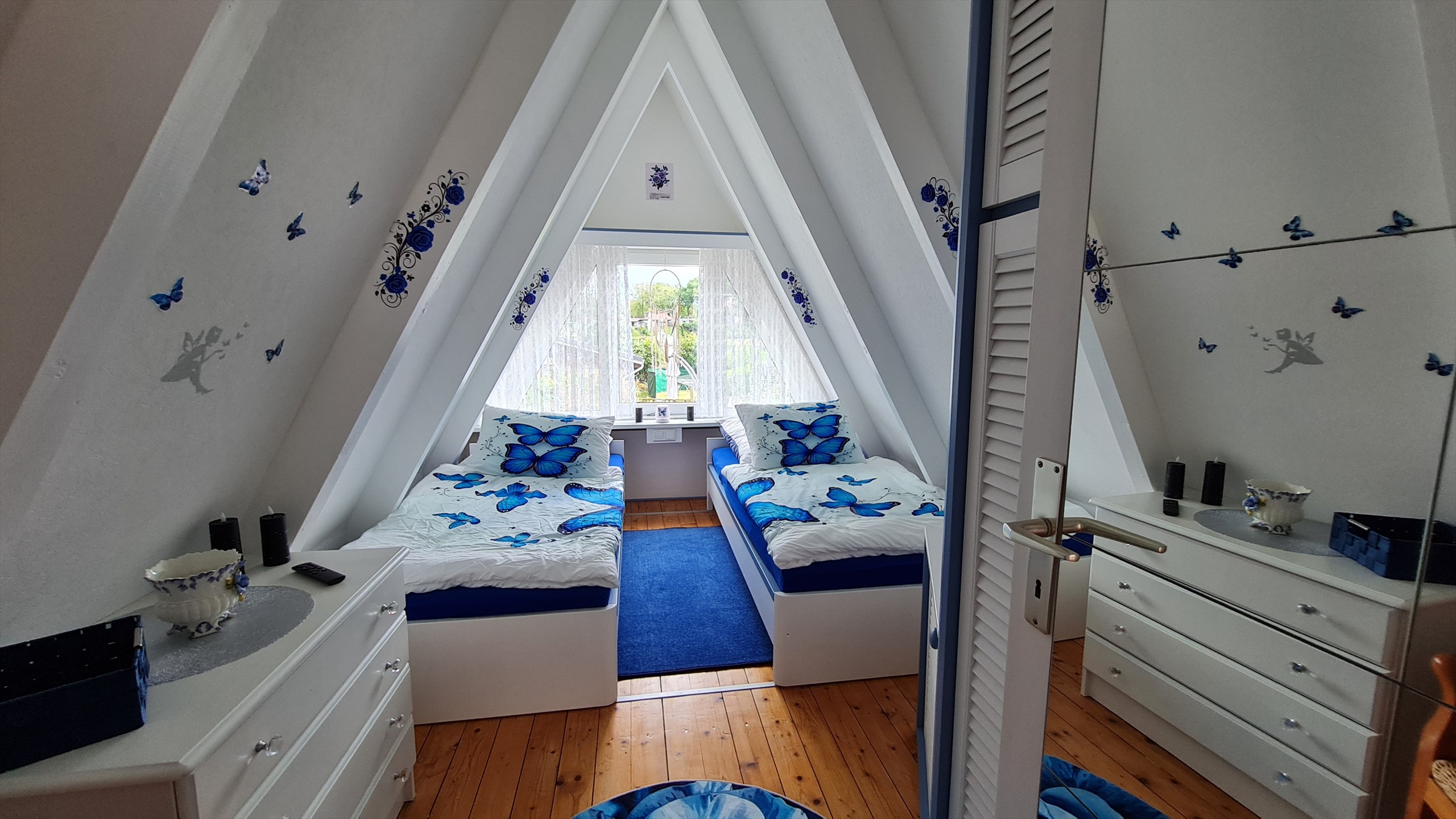 Helles Schlafzimmer mit blauen Akzenten unter dem Dach