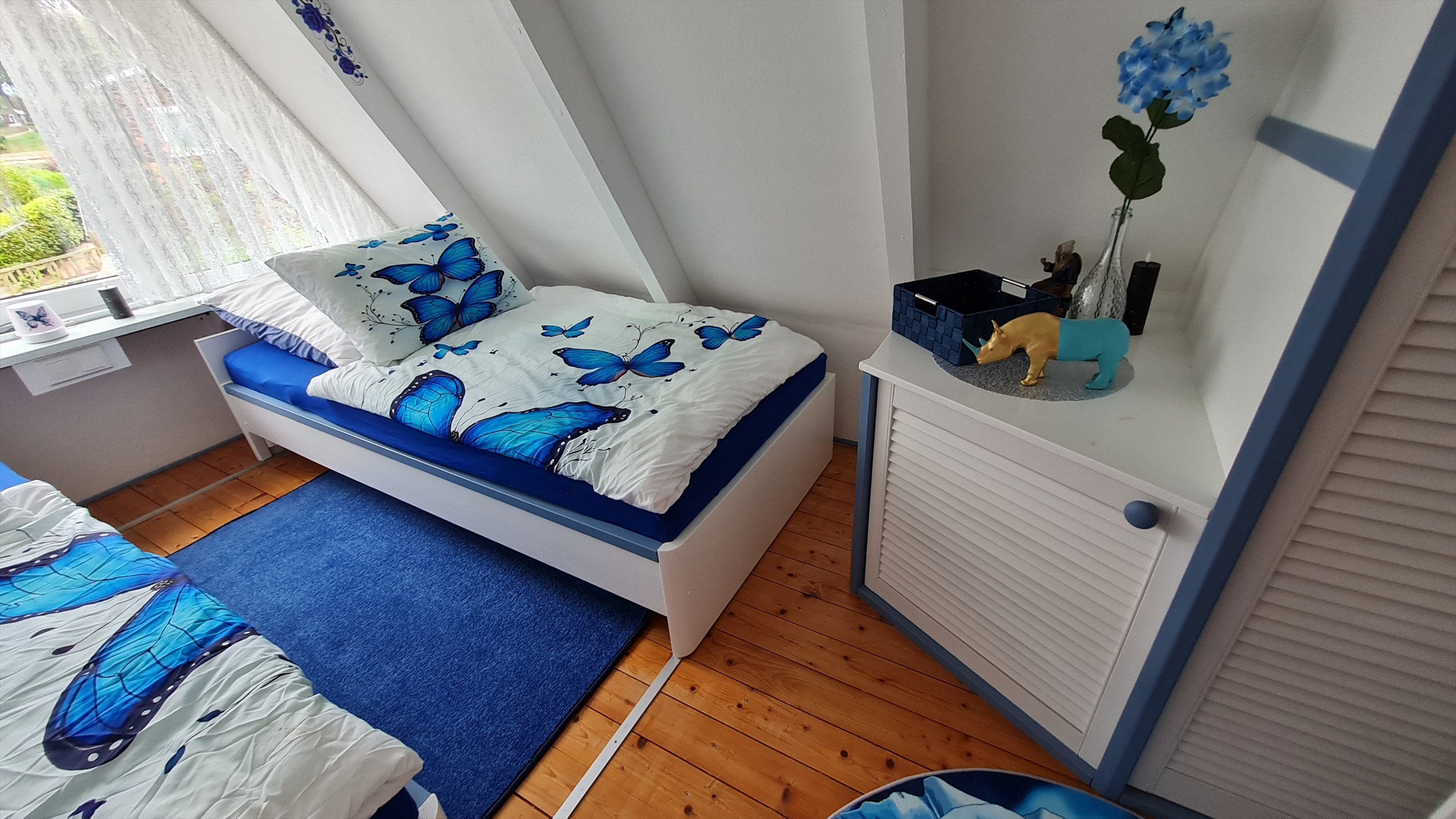 Helles Schlafzimmer mit blauen Akzenten unter dem Dach