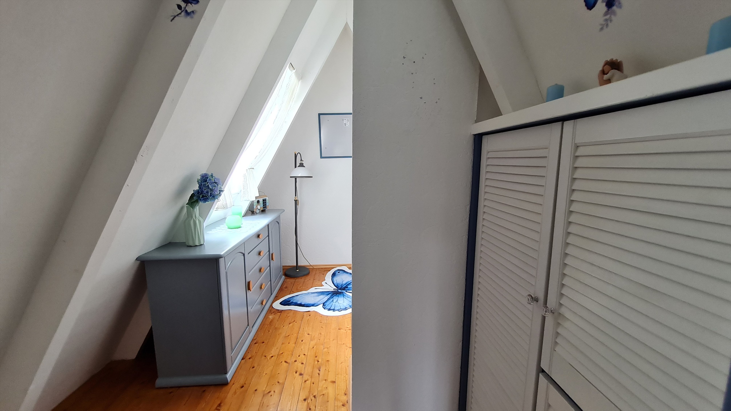 Helles Schlafzimmer mit blauen Akzenten unter dem Dach