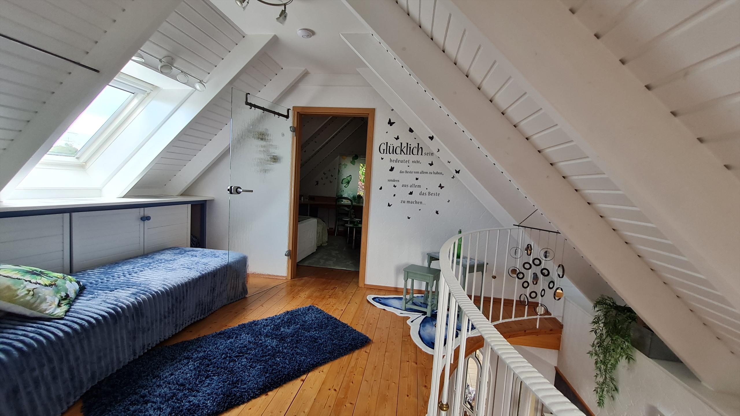 Helles Schlafzimmer mit blauen Akzenten unter dem Dach